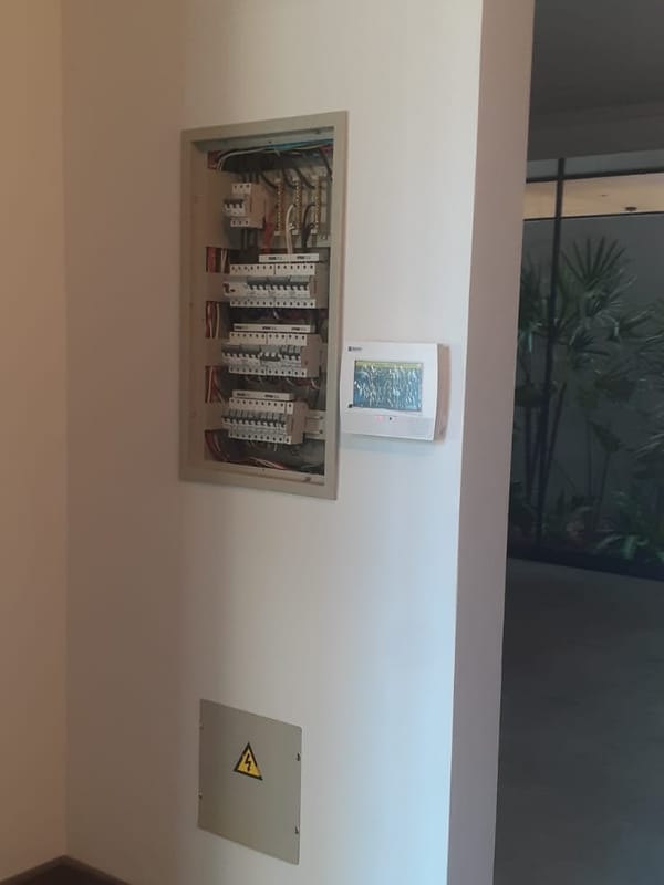 Tablero eléctrico embutido en la pared de un hall, junto a un panel de control